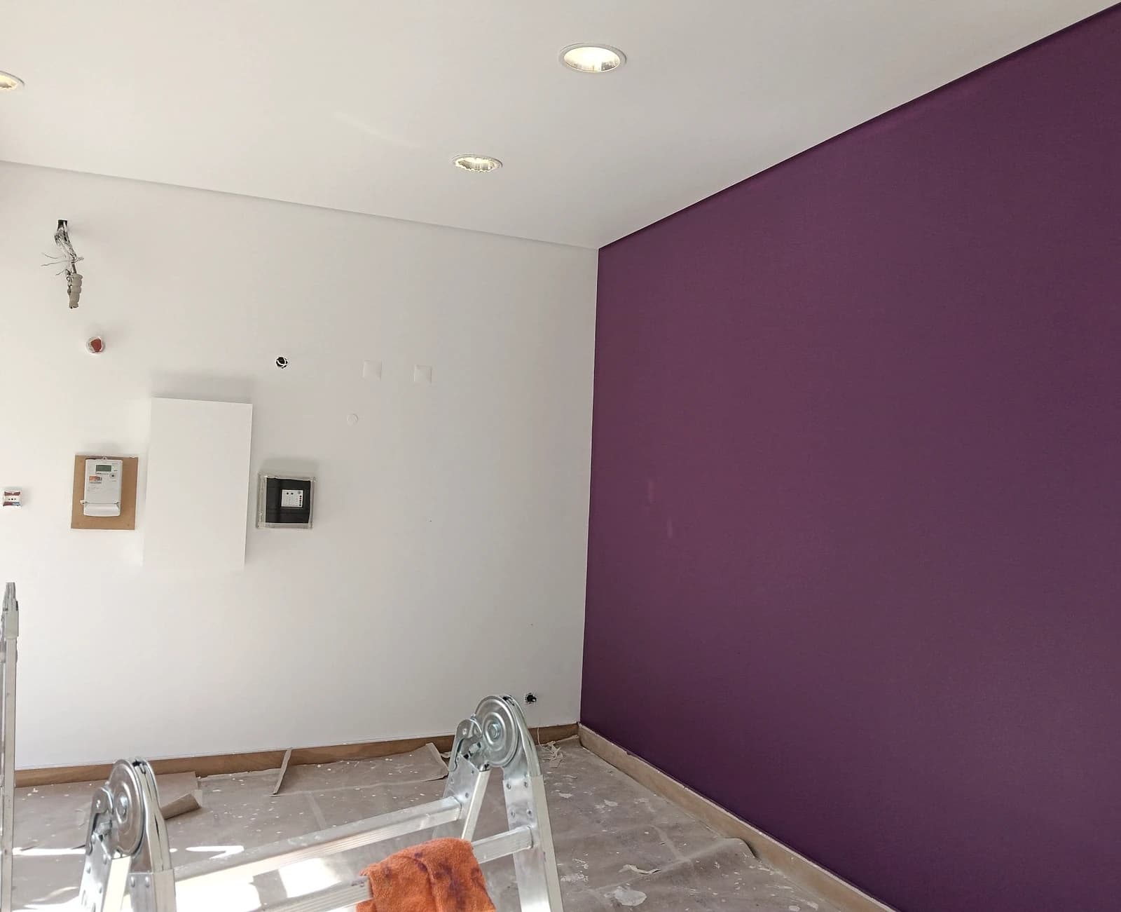 Sala com parede roxa e escadote, pintura em curso
