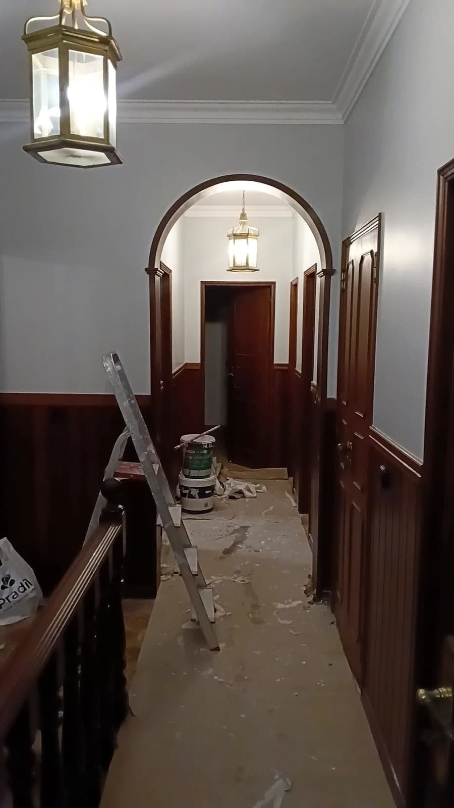 Corredor com lambrim de madeira e escadote, pintura em curso