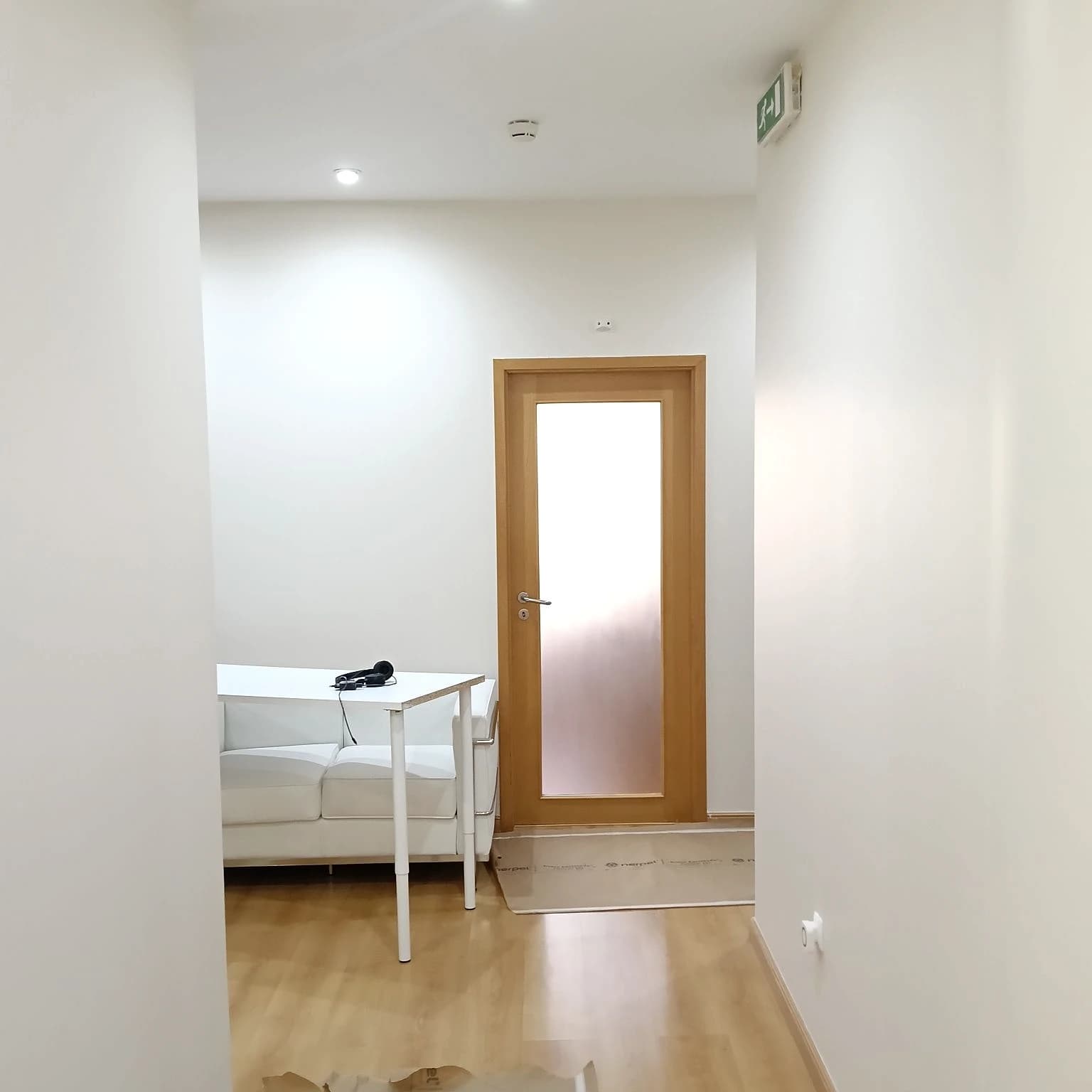 Sala pintada de branco com porta envidraçada de madeira e sofá branco